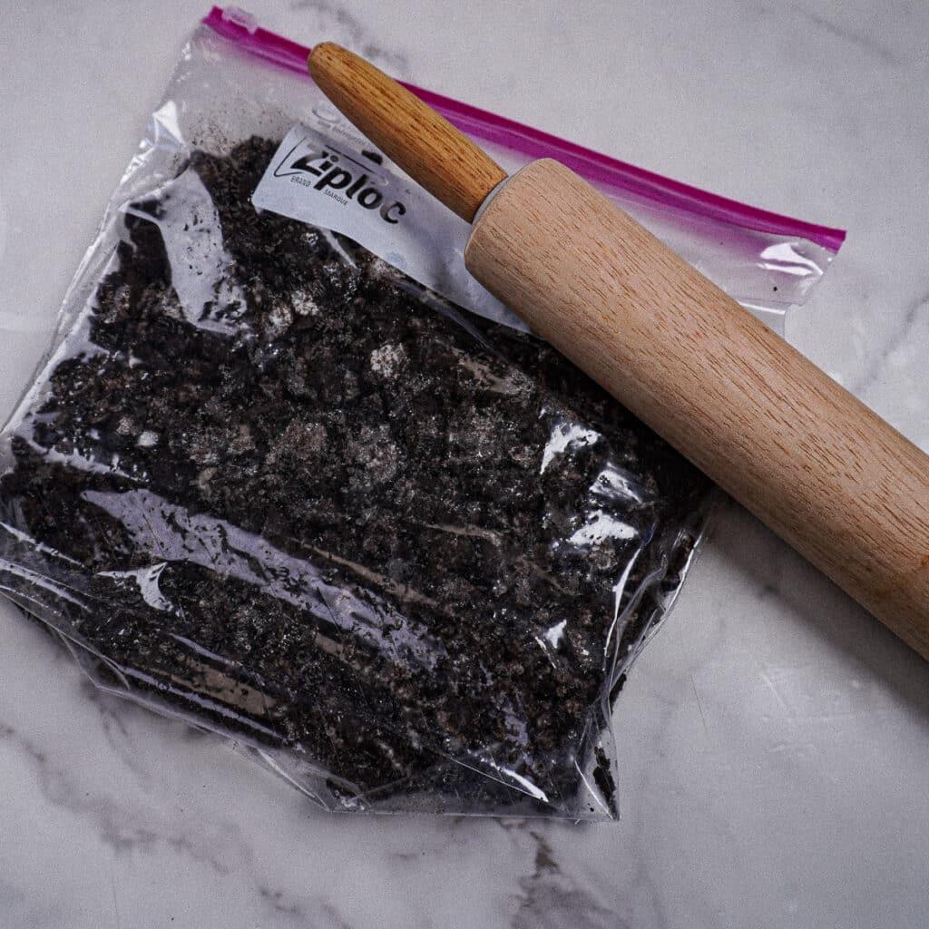 Crushed Oreos in a ziplock bag with a rolling pin