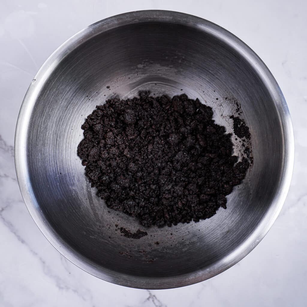 Oreos mixed with melted butter in a bowl