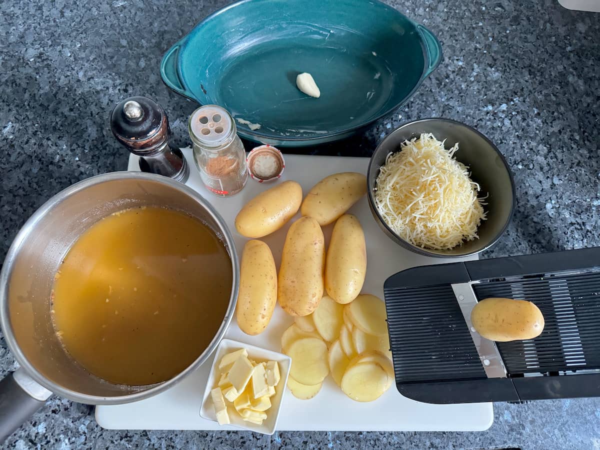 Ingredients for a Savoyard potato gratin including stock, potatoes, cheese, and seasonings