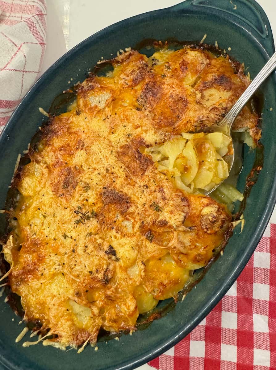 Large gratin dish with scalloped cooked potatoes topped with crusty cheese