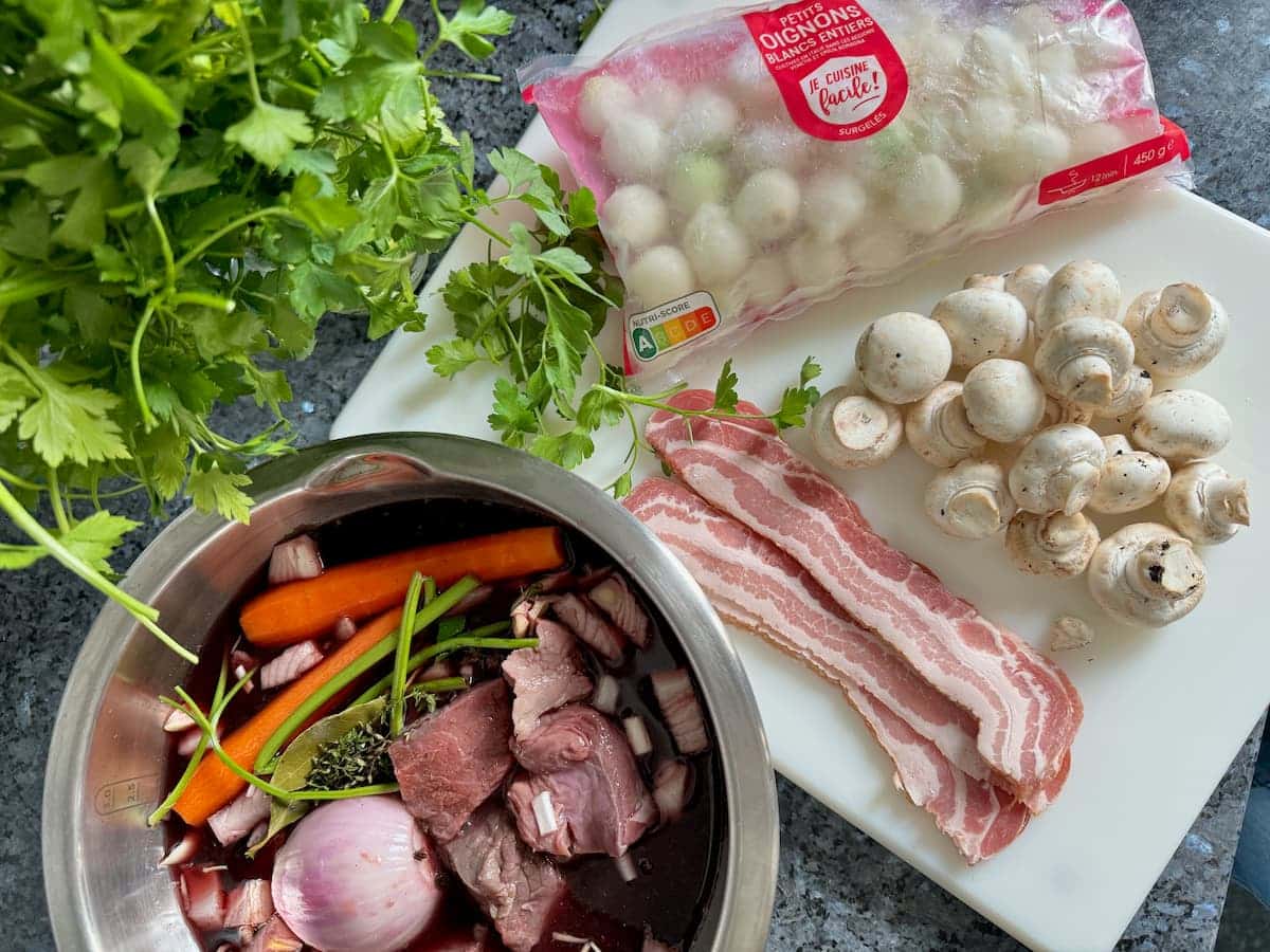 Beef stew with garnish ingredients: pearl onions, mushrooms, and bacon.