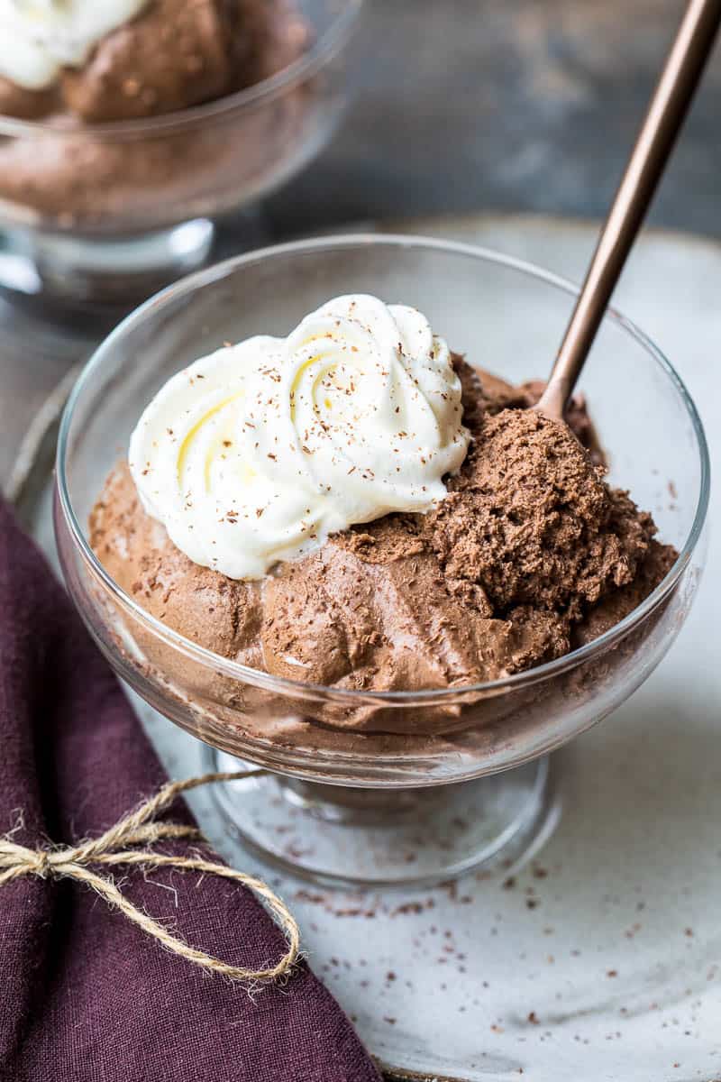 bowl of chocolate mousse with spoon and whipped cream