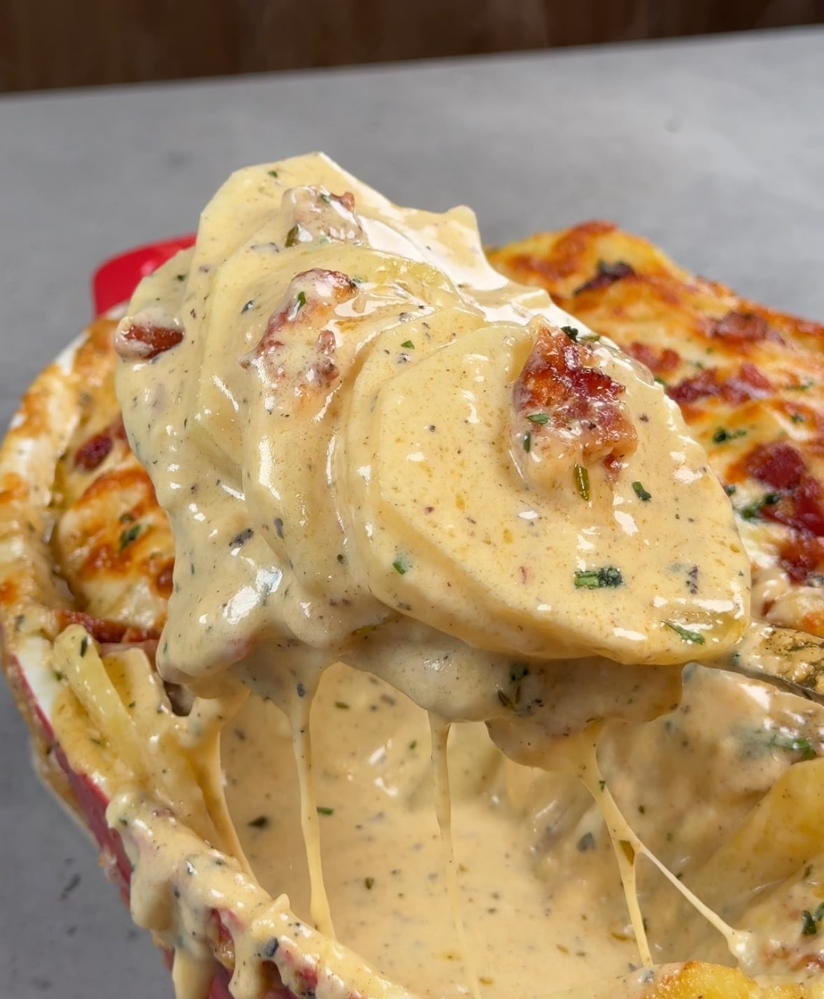 A spoon serving a scoop of au gratin potatoes.