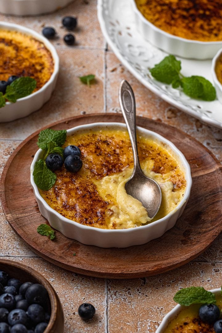 Vanilla Crème Brûlée in a ramekin, garnished with mint and blueberries.