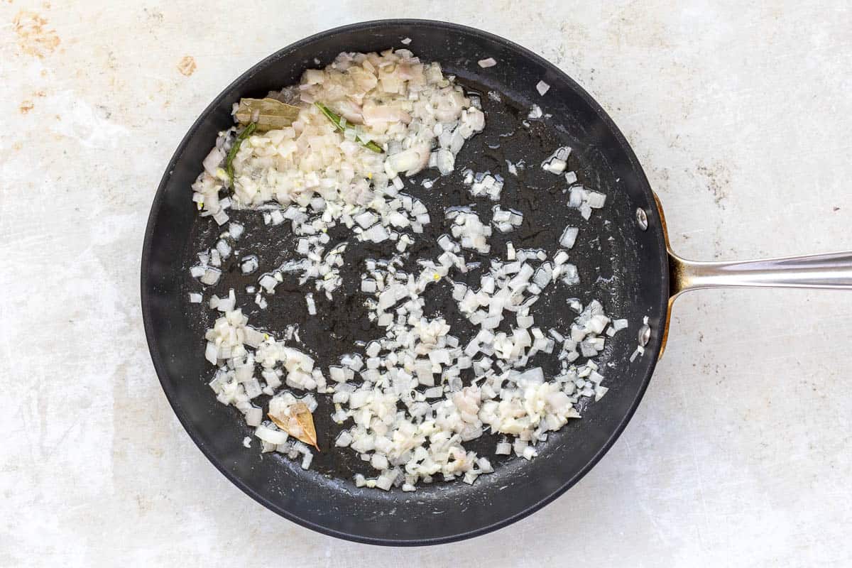 Sautéed shallots and herbs in a skillet.