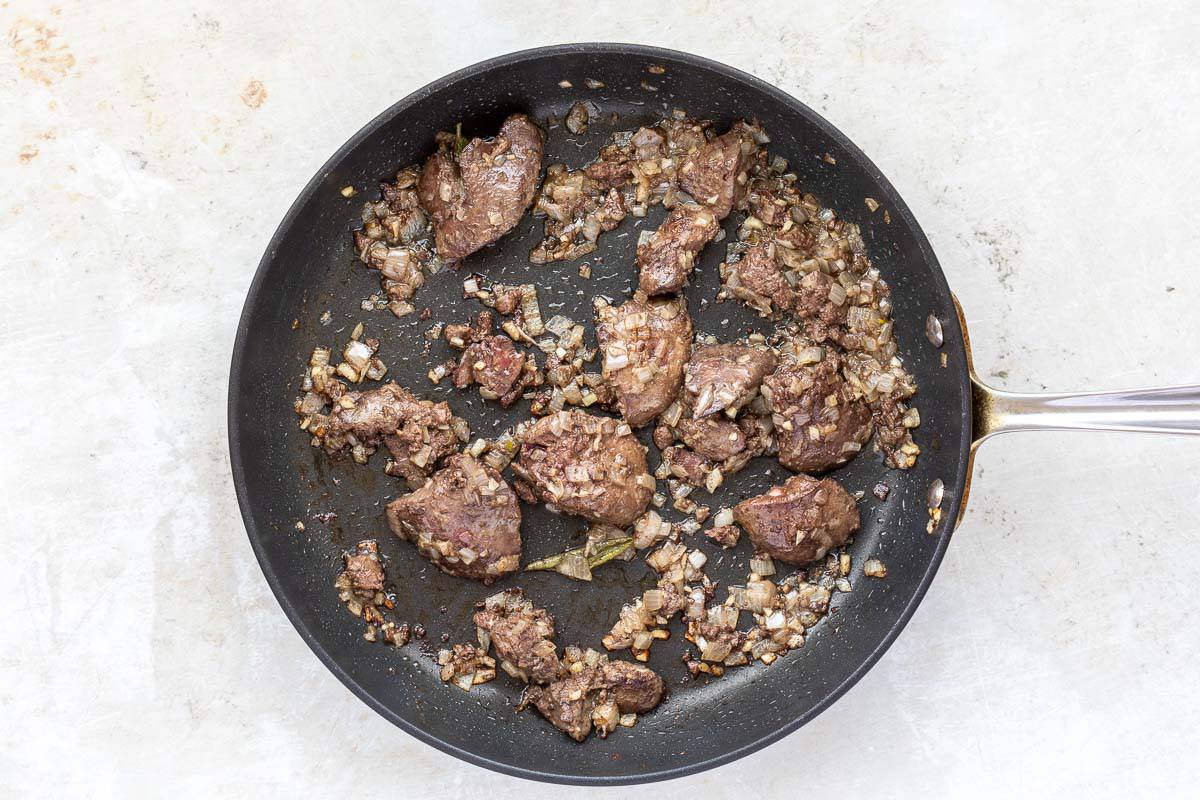 Sautéed chicken livers, shallots, and herbs in skillet.