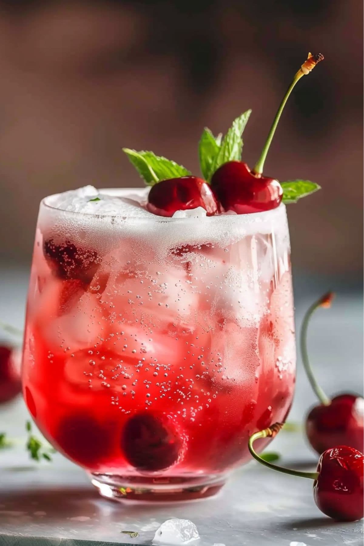 Cherry vanilla fizz served in an ice cold glass garnished with cherries and mint sprigs.