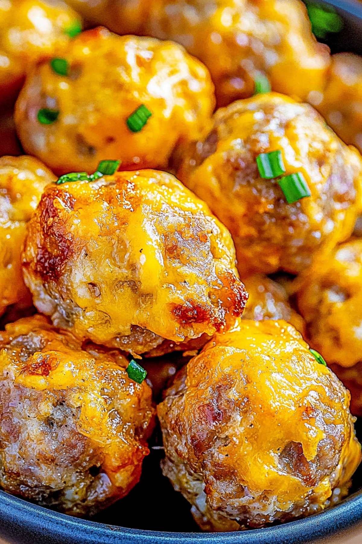 Bunch of cheesy pancake sausage balls served in a blue bowl.