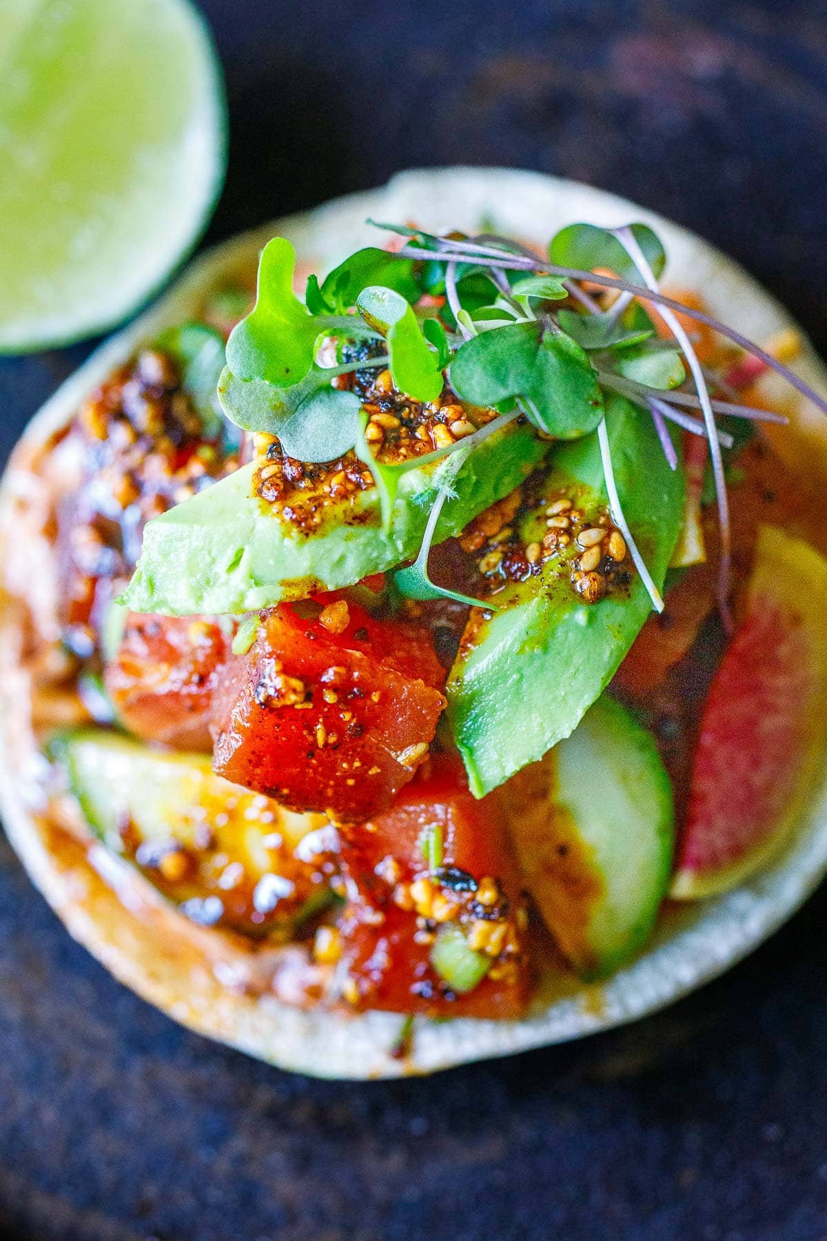 Ahi tuna tostada topped with avocado and microgreens.
