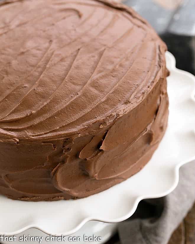 Homemade chocolate cake on a white pedestal.