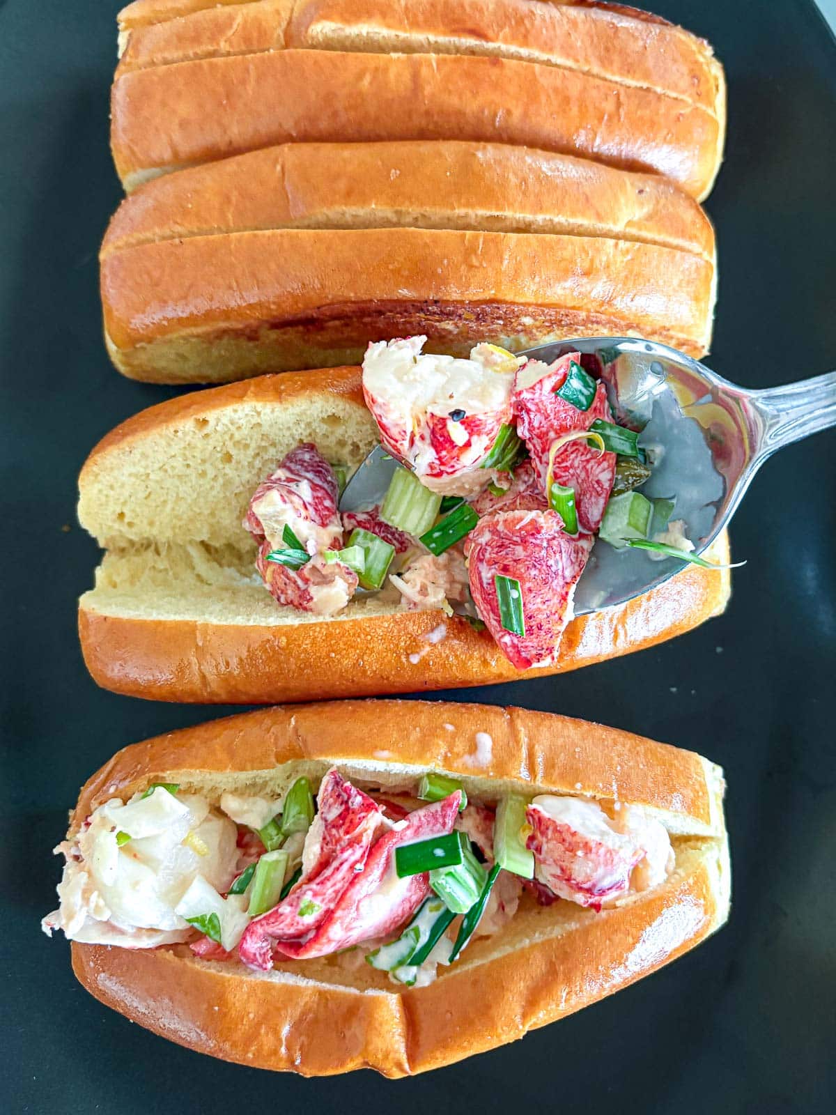 Lobster mixture being spooned into toasted buns.