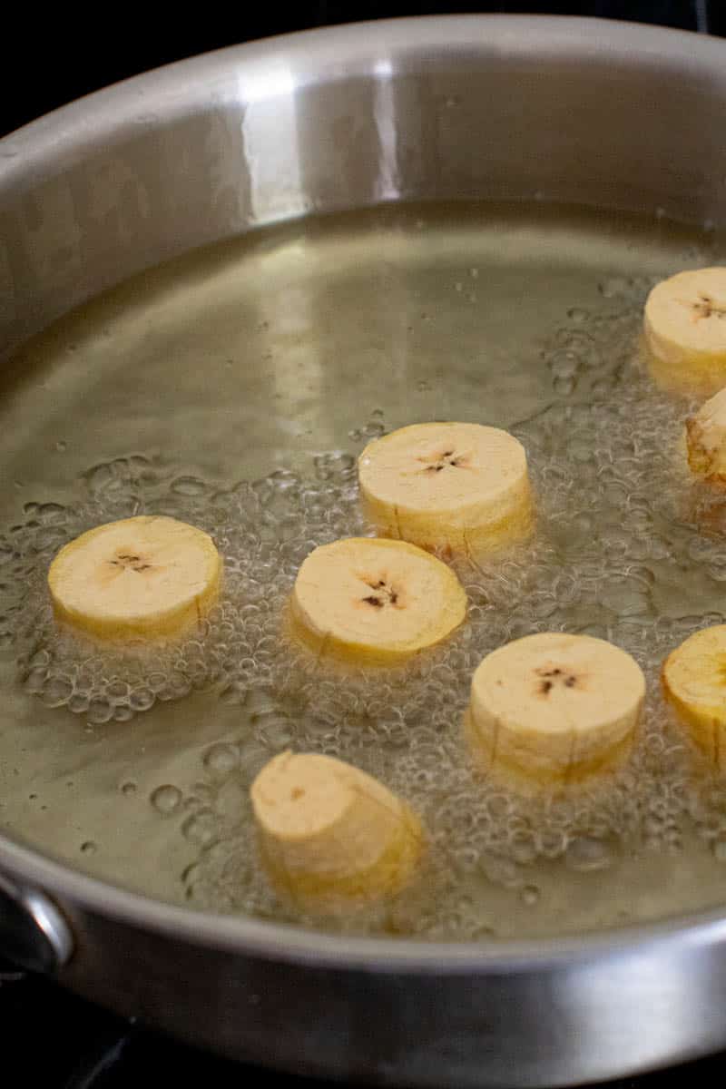 Green plantains frying in a skillet