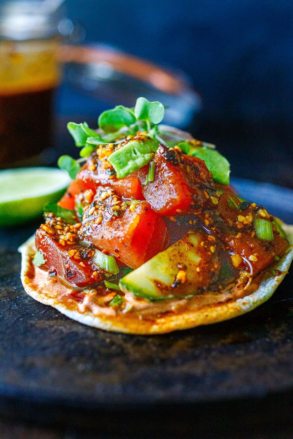 Tuna tostada with salsa macha, cucumber, avocado, and microgreens.