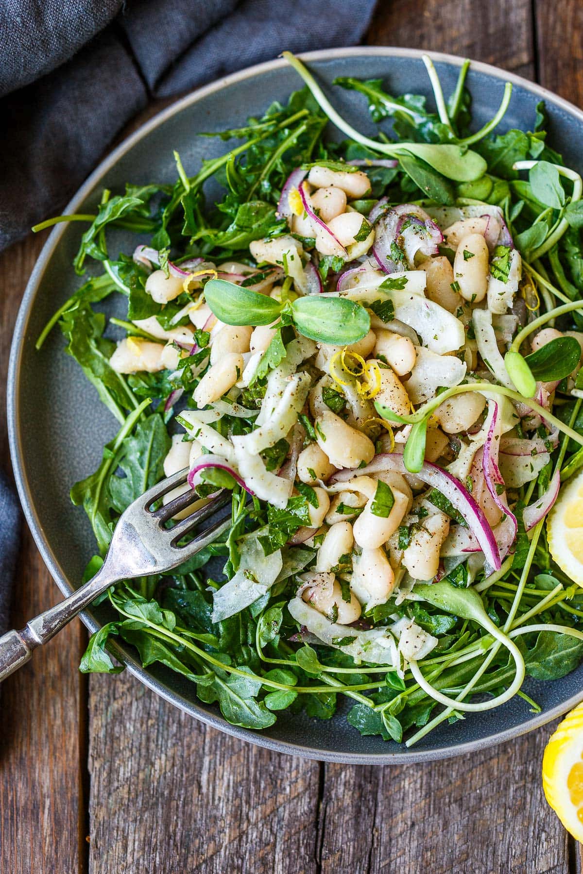White bean salad garnished with herbs and served over arugula.