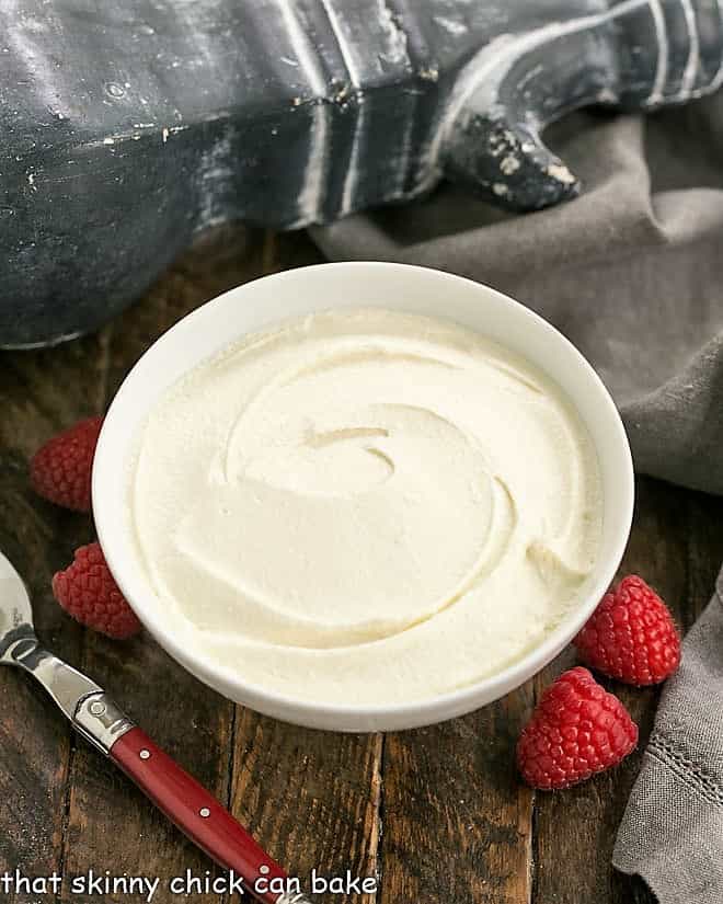 Homemade Mascarpone in a white bowl with fresh raspberries.
