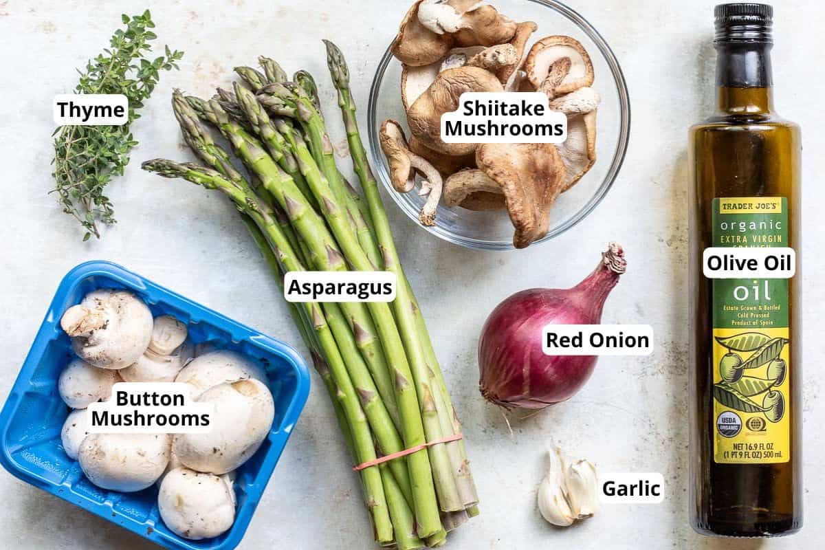 Ingredients for sautéed asparagus and mushrooms including thyme, mushrooms, asparagus, red onion, garlic, and olive oil