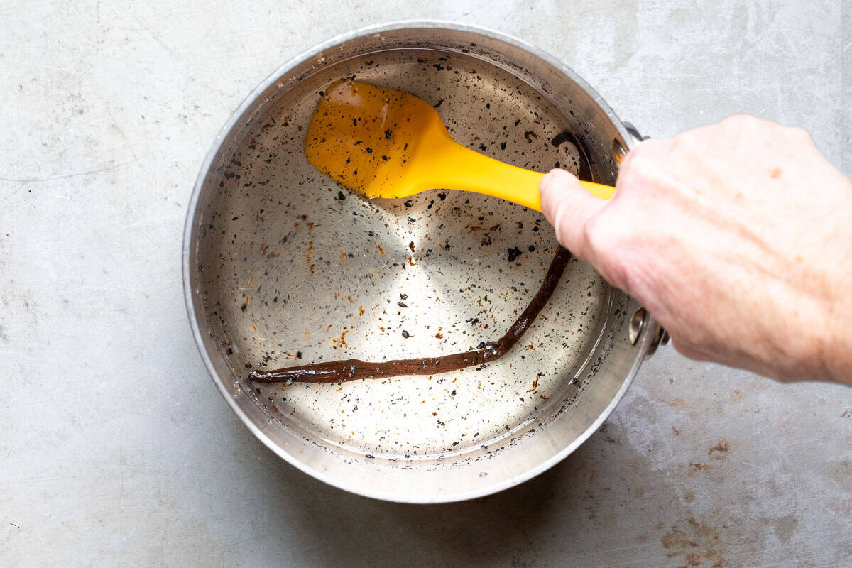 Using a spatula to blend together the vanilla bean seeds in syrup.