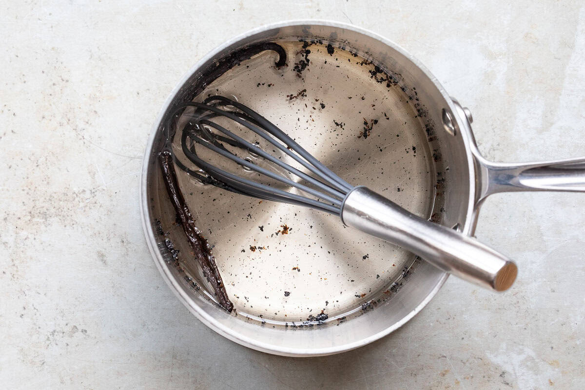 Vanilla bean and seeds infusing in syrup inside a saucepan.