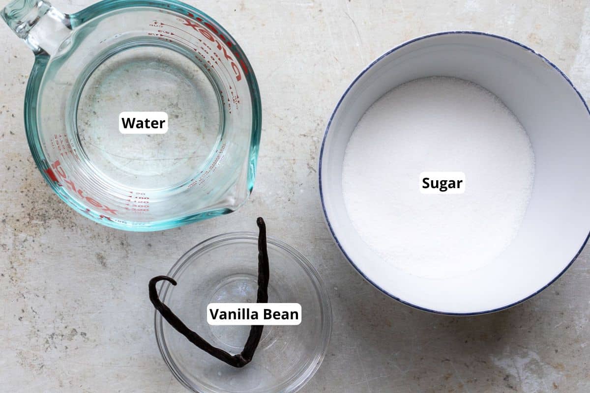 Ingredients for Vanilla Bean Simple Syrup: a measuring cup of water, a bowl of sugar, and a vanilla bean.