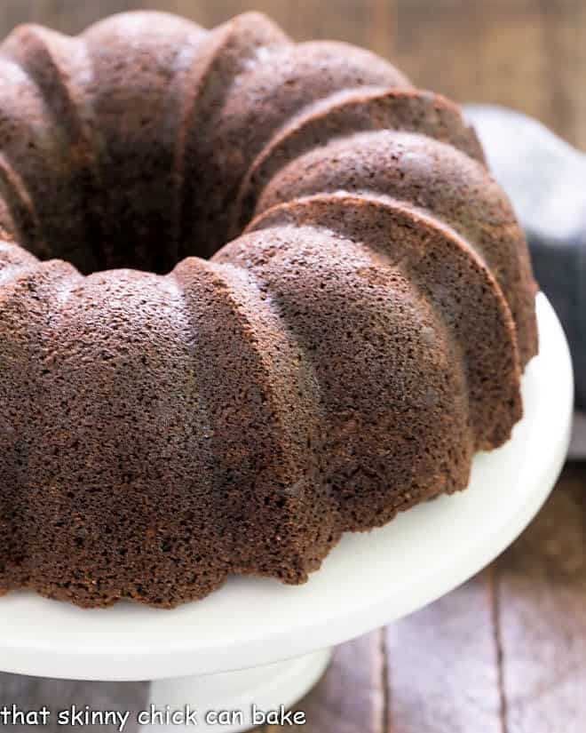 Chocolate Zucchini Bundt Cake - the addition of grated zucchini makes for a moist, delectable chocolate cake! Chocolate Zucchini Bundt Cake on a white cake plate.