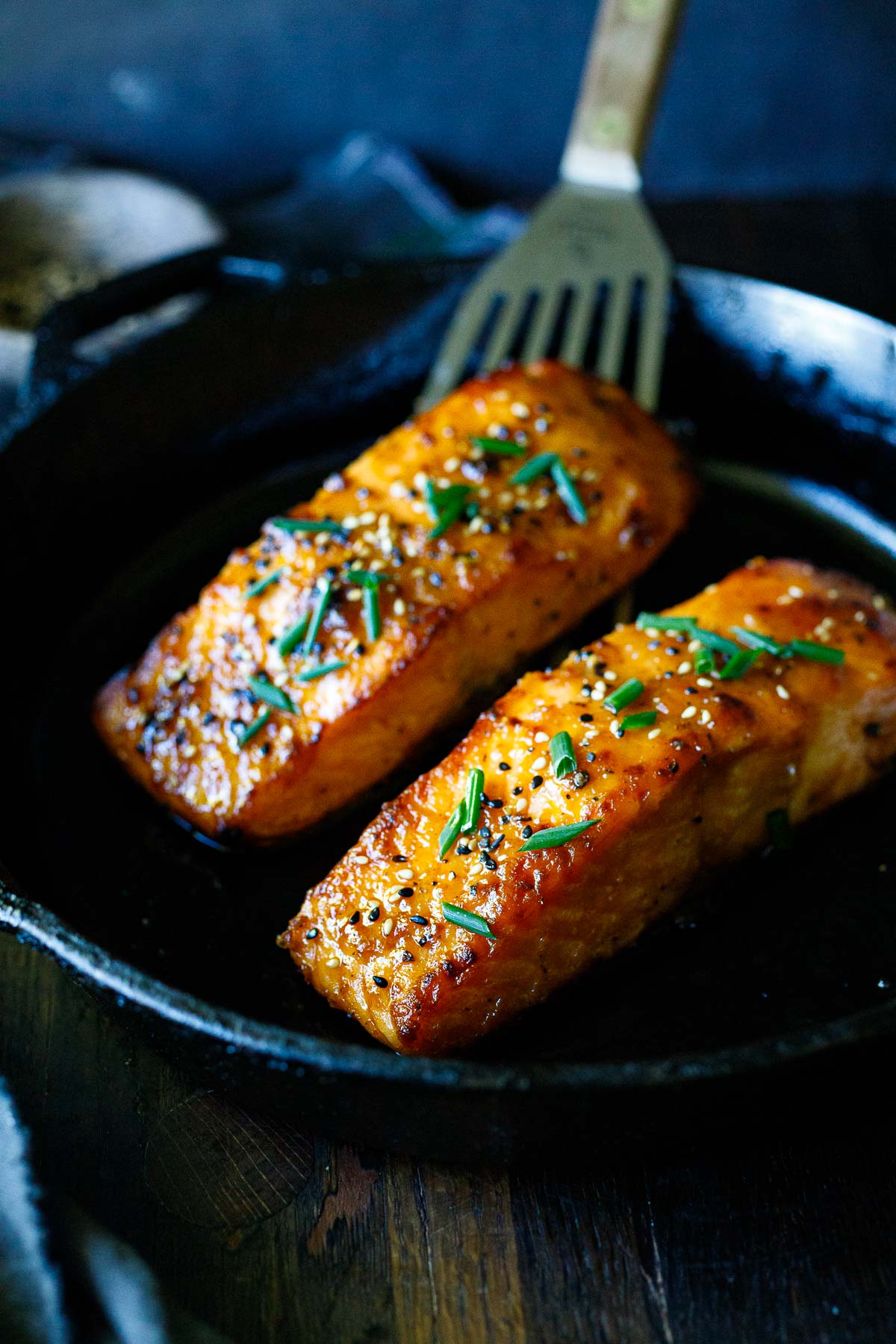 Broiled salmon in a skillet with miso, chives, and sesame seeds.