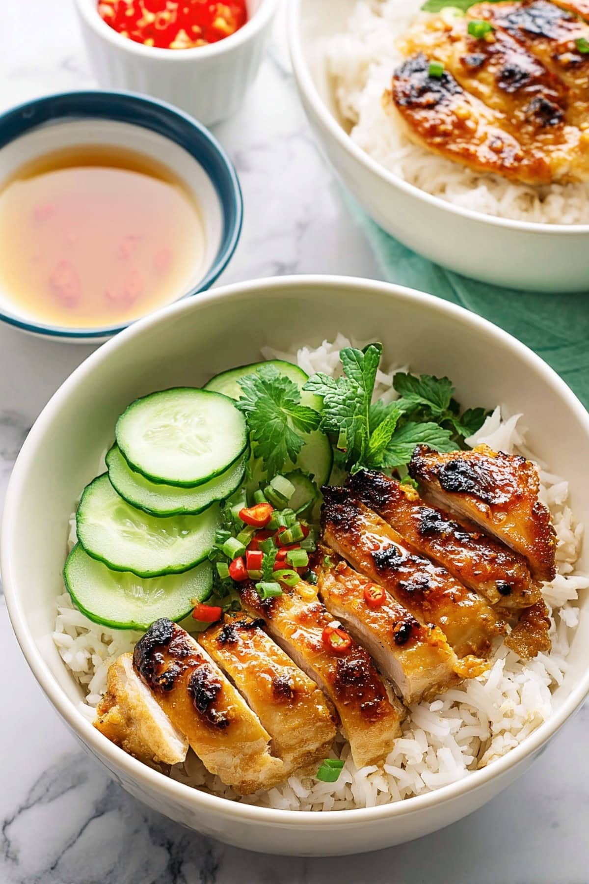 Vietnamese Lemongrass Chicken with cucumber over rice in a bowl.