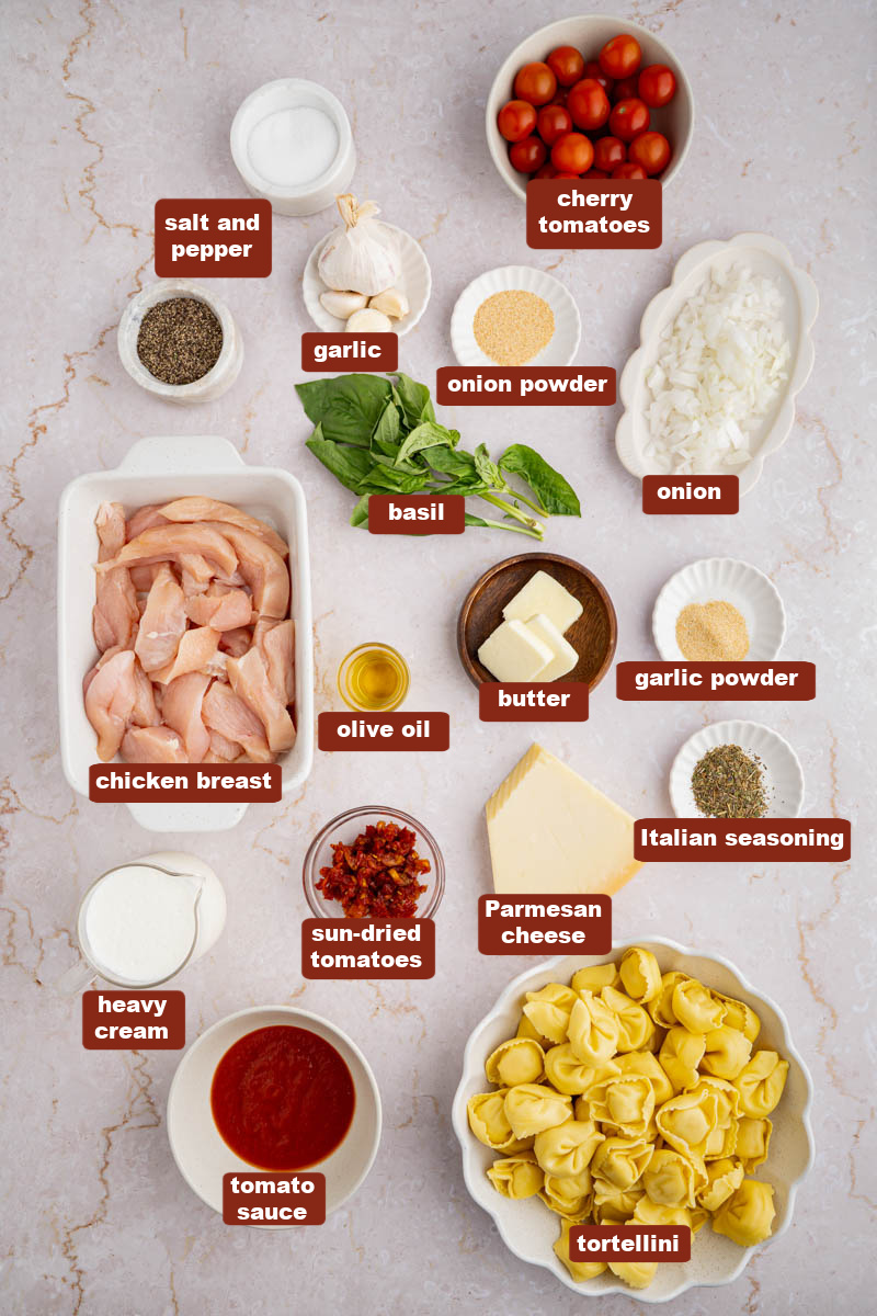 All the ingredients for creamy chicken tortellini in bowls on a white countertop.