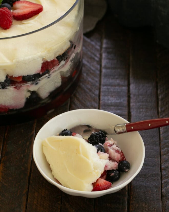A delicious bowl of berry trifle with a spoon beside the serving bowl.