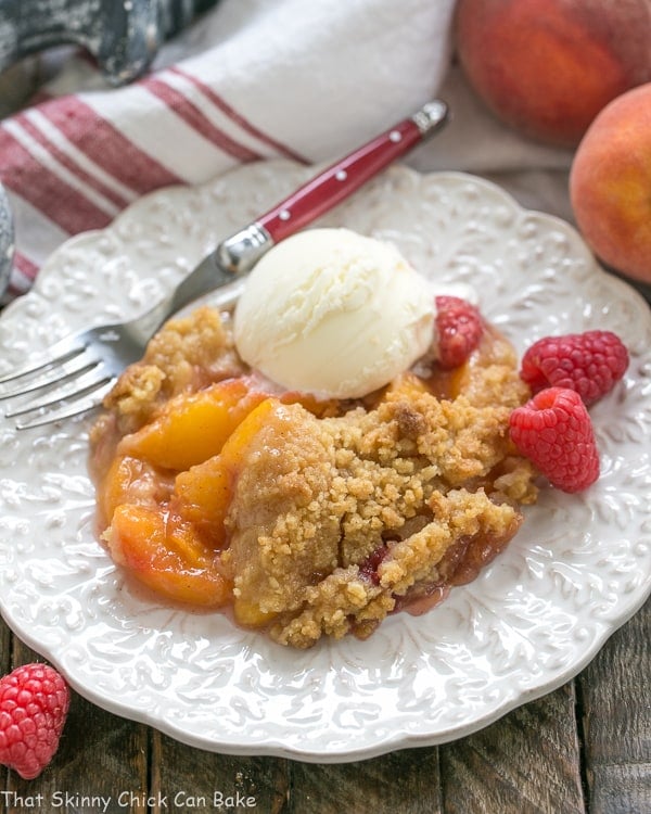 Peach Raspberry Crisp - A heavenly summer dessert that’s easy and unforgettable! Peach Raspberry Crisp on a white plate topped with a scoop of ice cream.