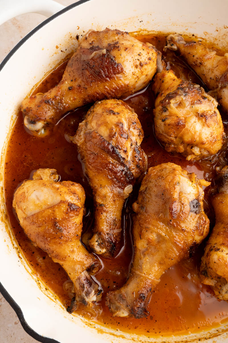 Baked chicken drumsticks in a pan before serving.